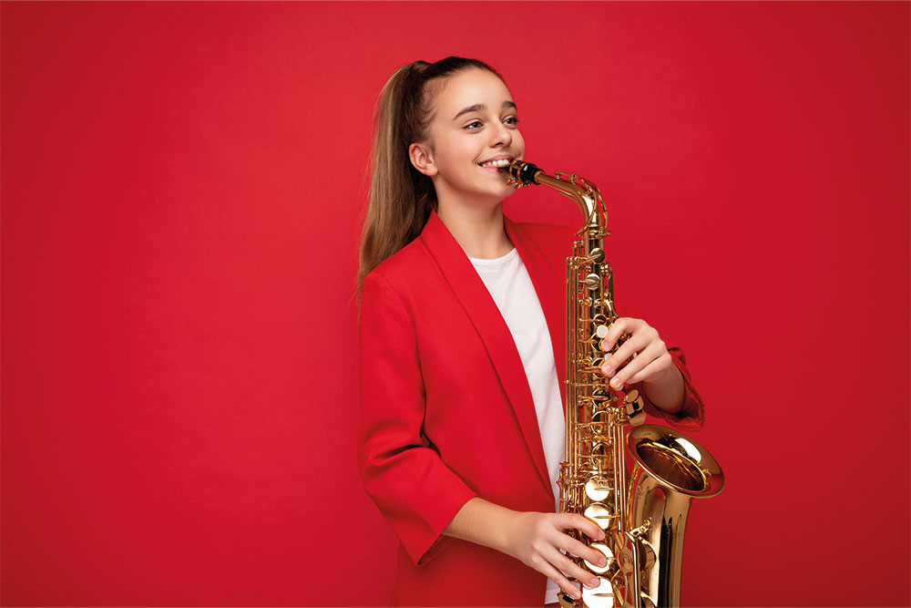 Das Bild der Musikschule Odenwald zeigt eine junge Frau mit Saxopjon. Der Hintergrund ist rot.